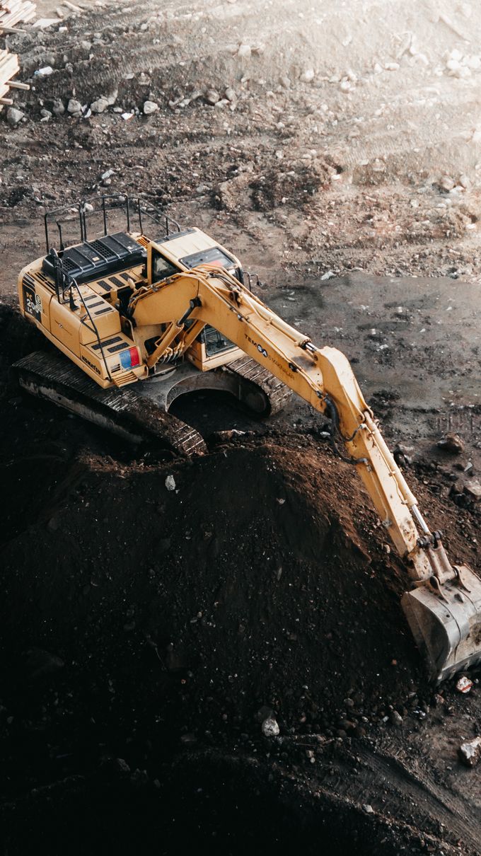An excavator digging dark soil, seen from above
