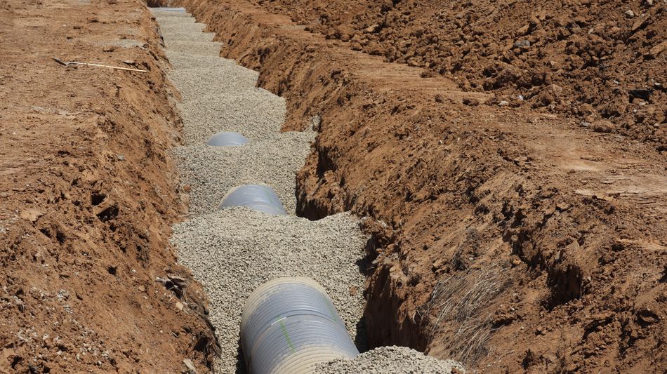 New pipe set in a gravel bed inside an open trench